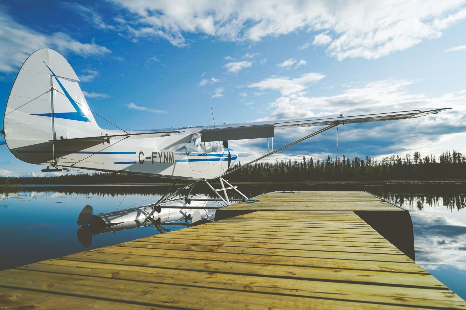 A floatplane tied to a dock on a calm boreal lake.